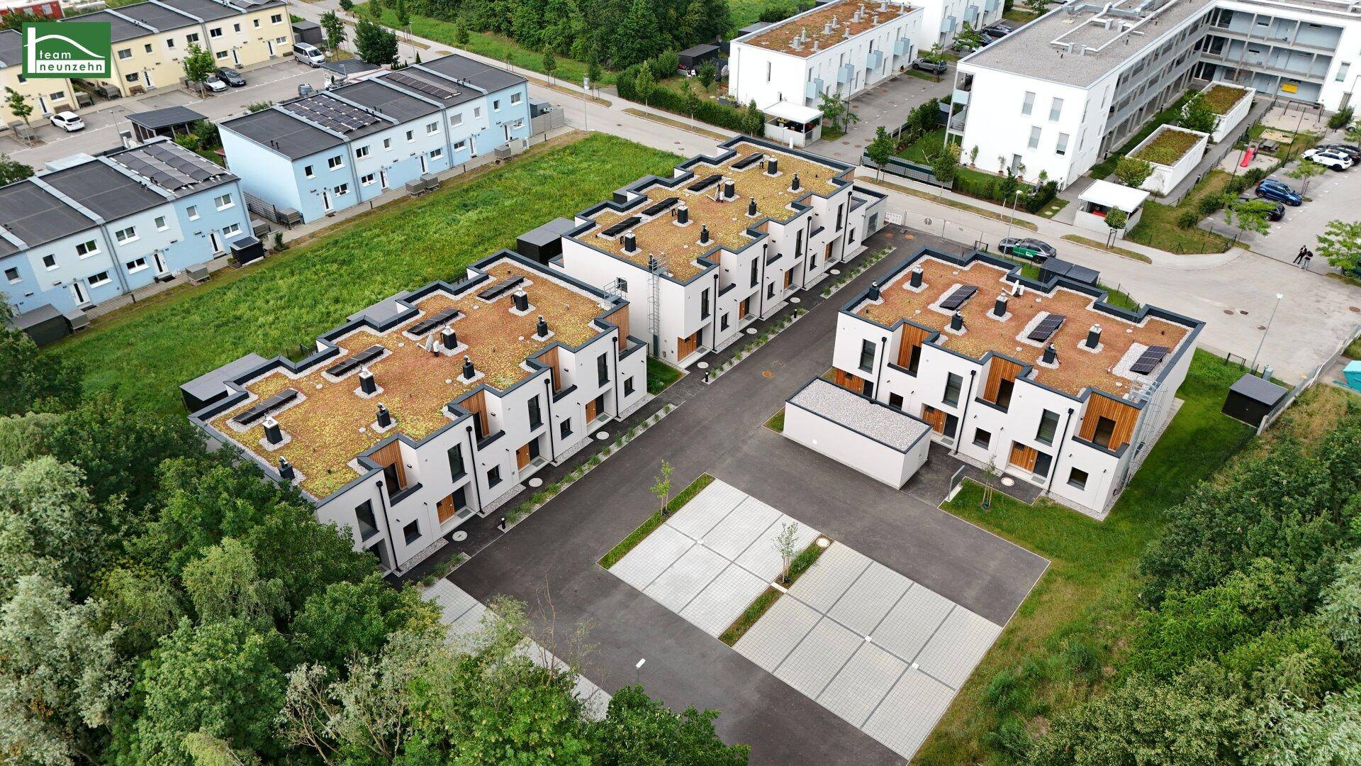 Übersicht der neuen Wohnanlage mit Gründächern und angrenzenden Parkplätzen in ländlicher Umgebung.