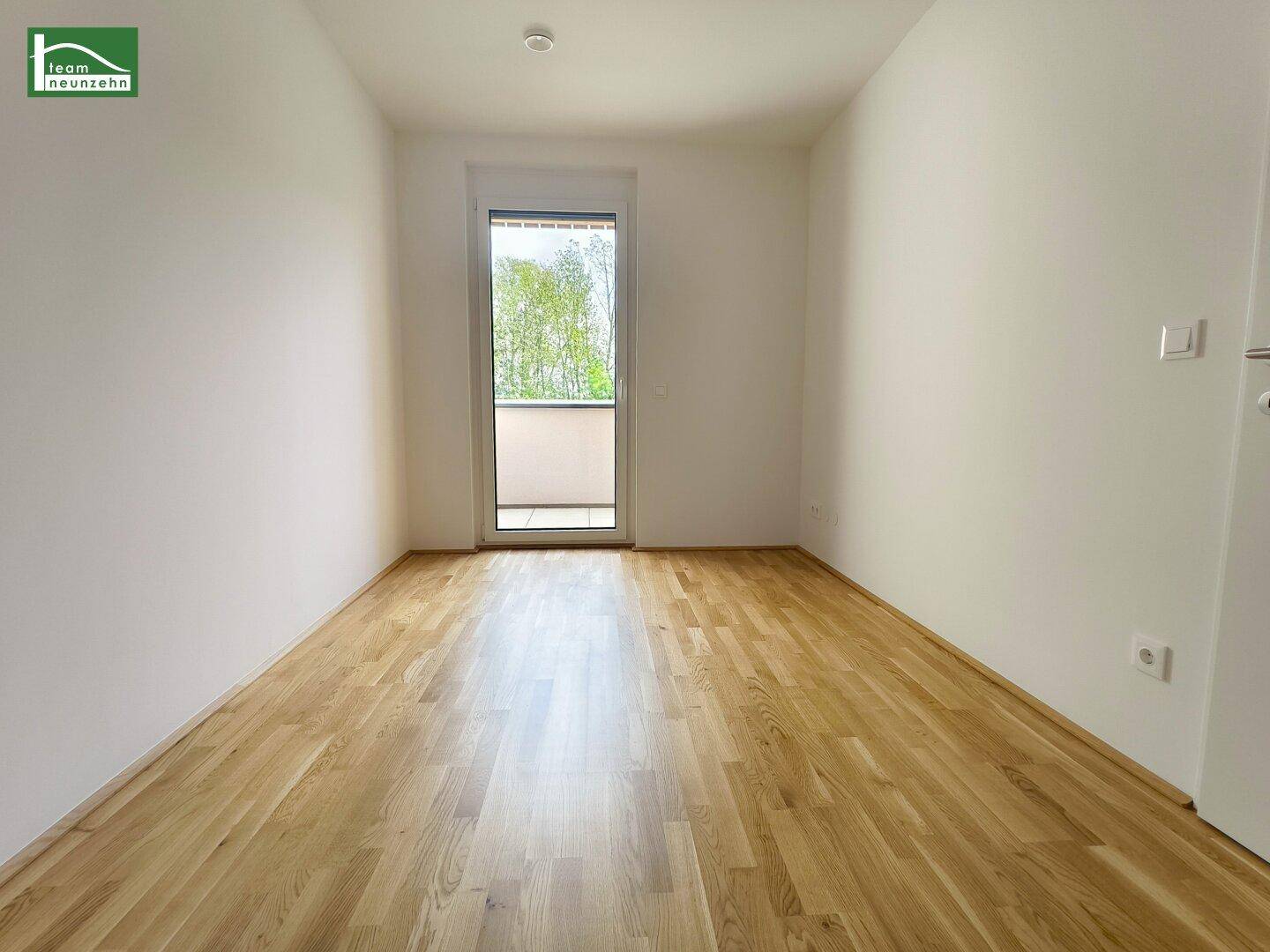 Freundliches Zimmer mit Parkettboden und Balkonzugang, perfekt als Schlaf- oder Arbeitszimmer.