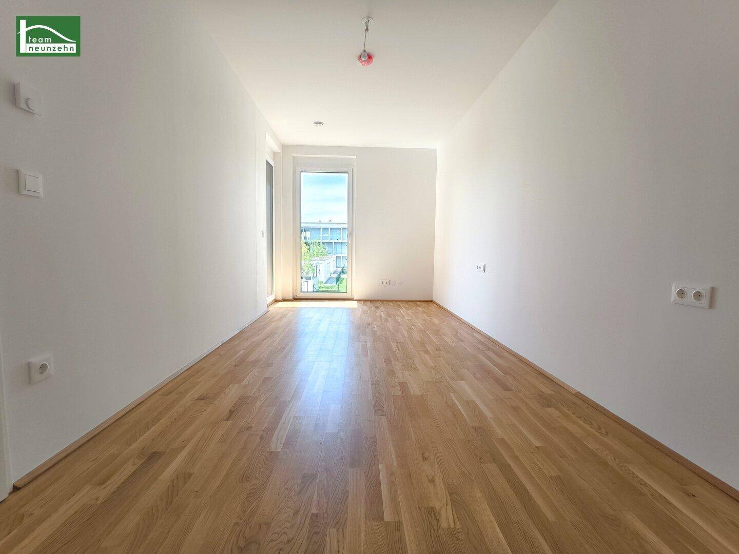 Helles Zimmer mit Parkettboden und Zugang zu einem kleinen Balkon, ideal als Schlafzimmer.