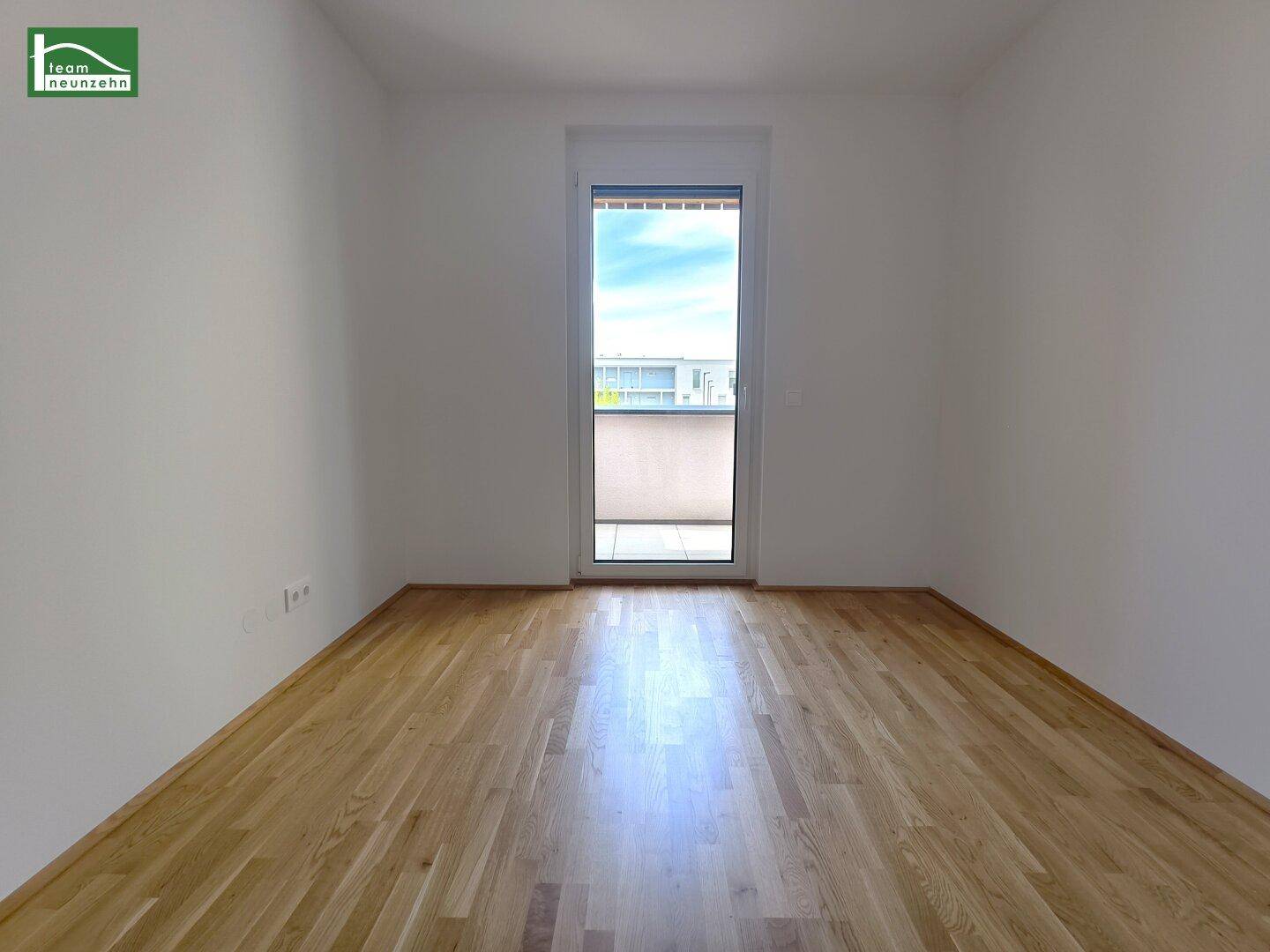 Lichtdurchflutetes Zimmer mit Parkettboden und direktem Zugang zum Balkon, mit Blick ins Freie.