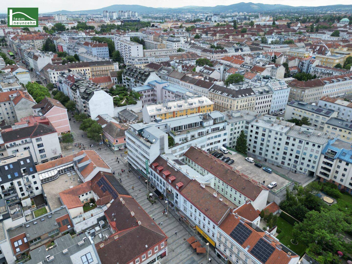 Detaillierte Luftaufnahme eines belebten Stadtviertels mit vielfältigen Wohn- und Geschäftsgebäuden.