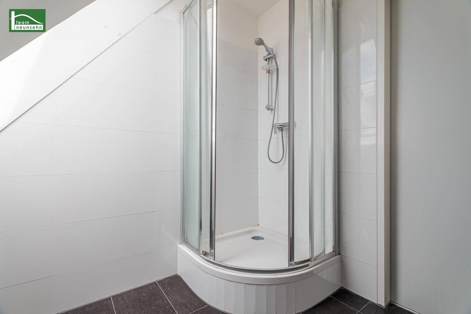 Badezimmer mit weiß gefliesten Wänden und einer praktischen Duschkabine, sauber und funktional.