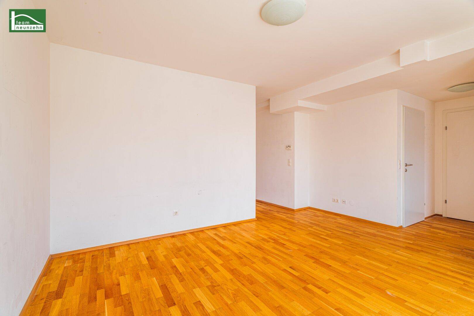 Heller, leerer Raum mit Holzparkett und weißen Wänden, bereit zur individuellen Gestaltung.