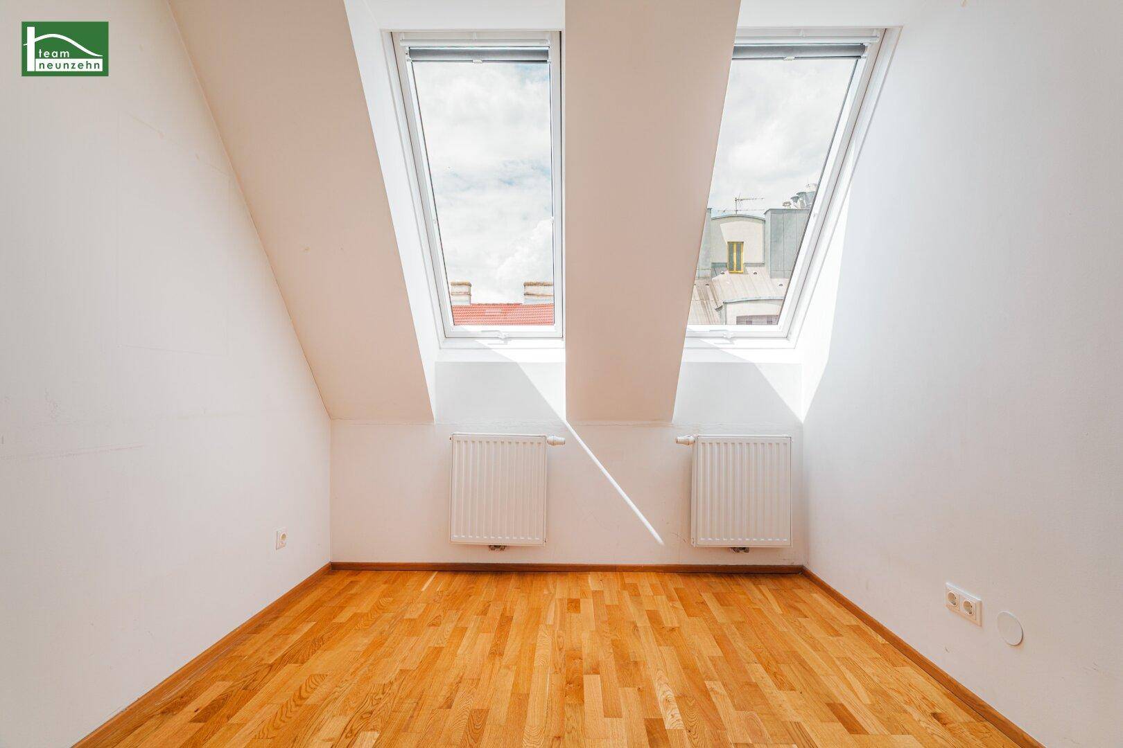 Helles Schlafzimmer im Dachgeschoss mit zwei großen Dachfenstern und Parkettboden für viel Licht.