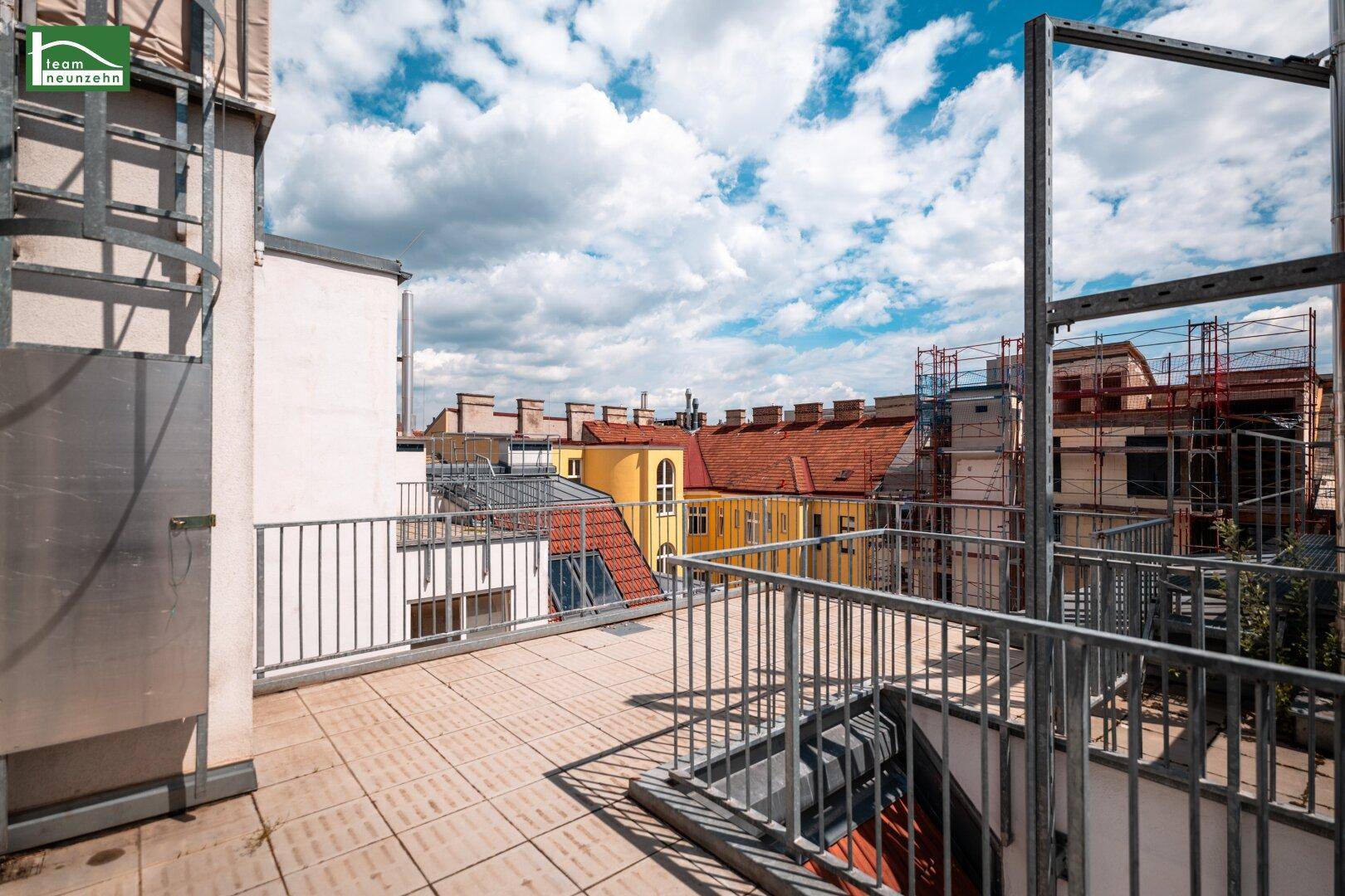 Weitläufige Dachterrasse mit Metallgeländer und Panoramablick auf die umliegende Stadtarchitektur.