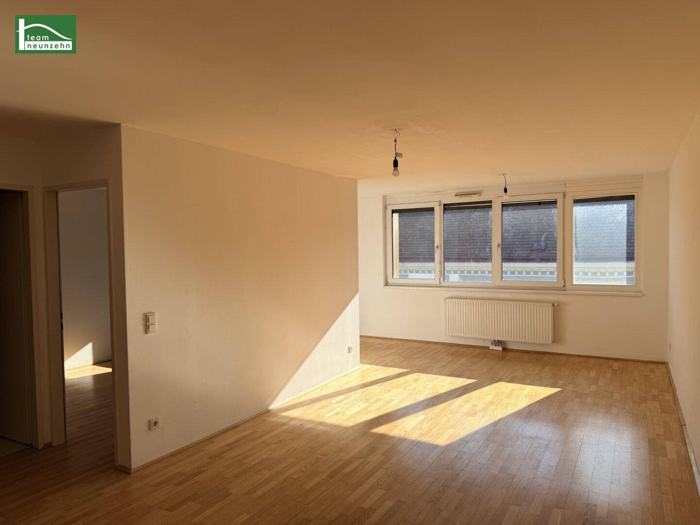 Lichtdurchfluteter Wohnbereich mit Holzboden und viel Sonnenschein, der den Raum erhellt.