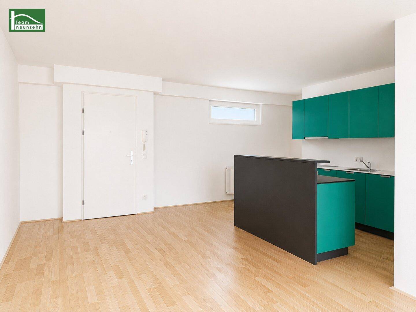 Offener Wohnbereich mit moderner Küche in Türkis und dunkler Theke, ideal für geselliges Kochen.