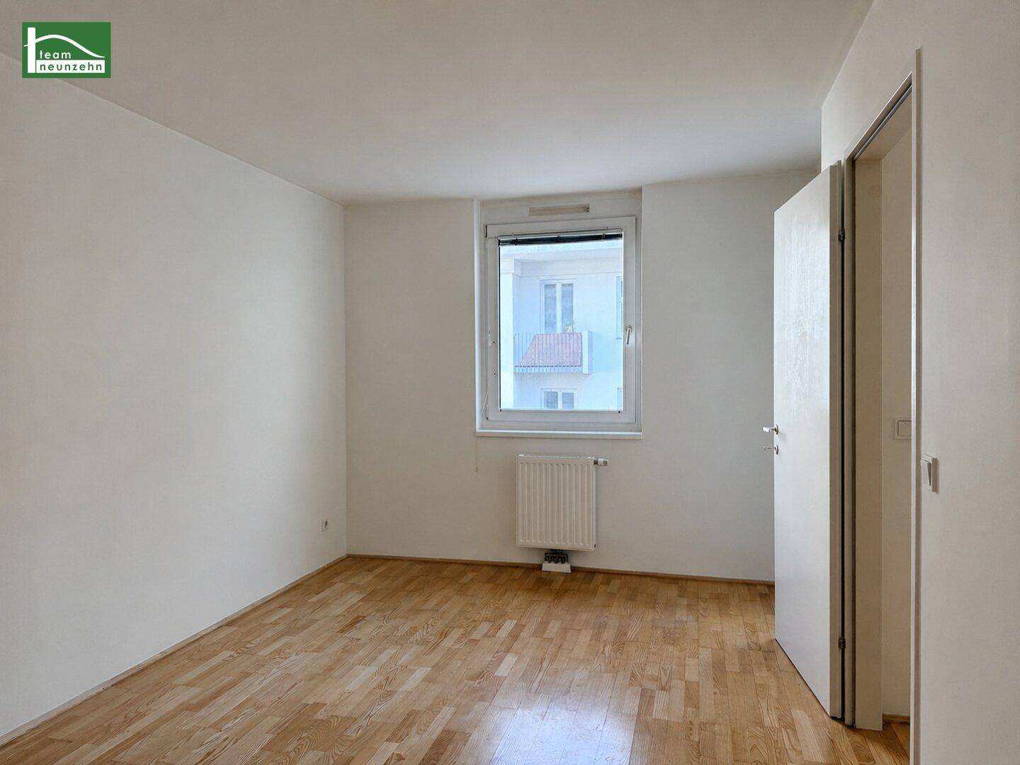 Heller Raum mit Parkettboden, weißen Wänden und einem Fenster, ideal als Wohn- oder Schlafzimmer.