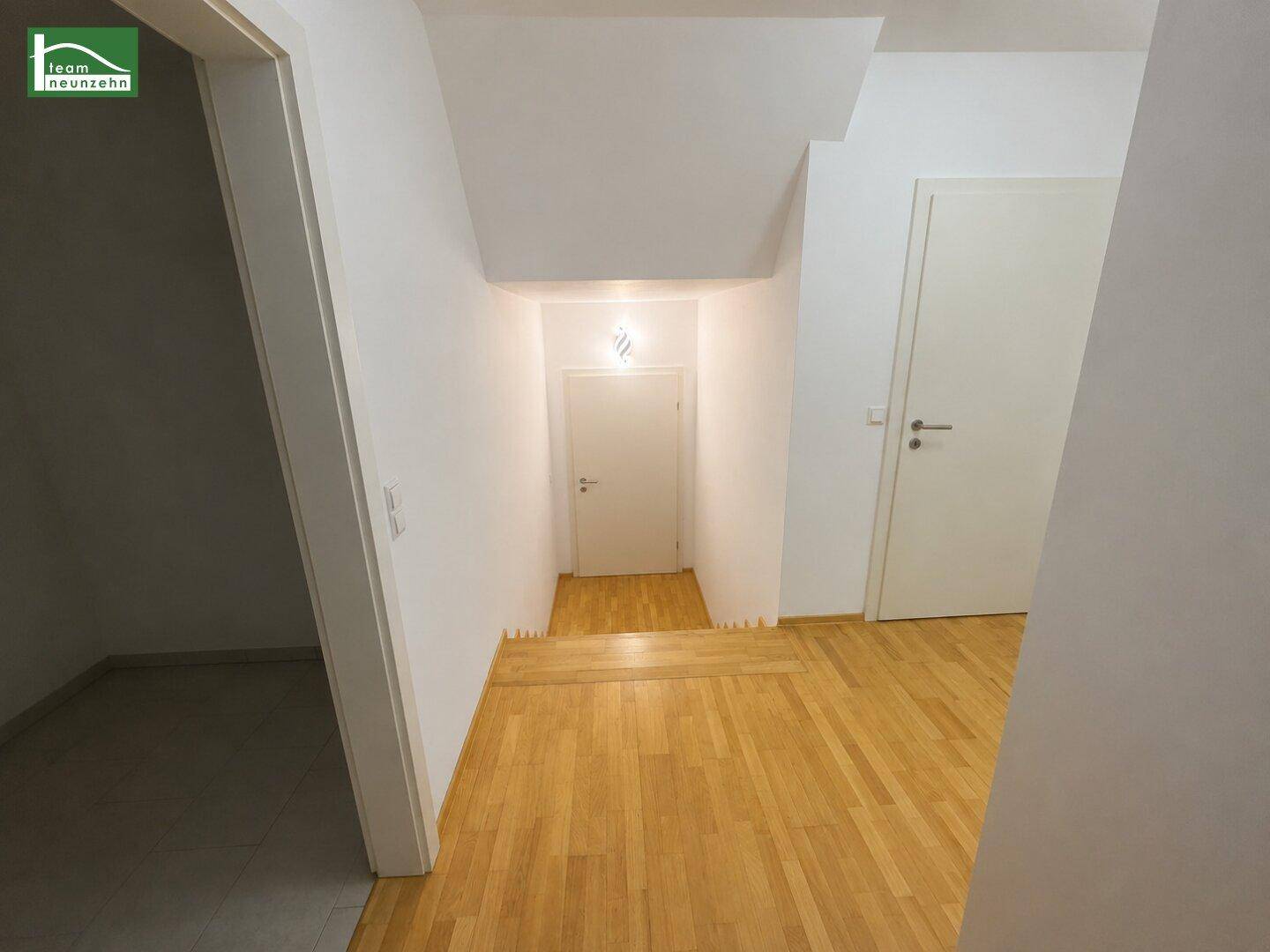 Heller Flur mit Holzboden und Zugang zu weiteren Räumen sowie einer Treppe.