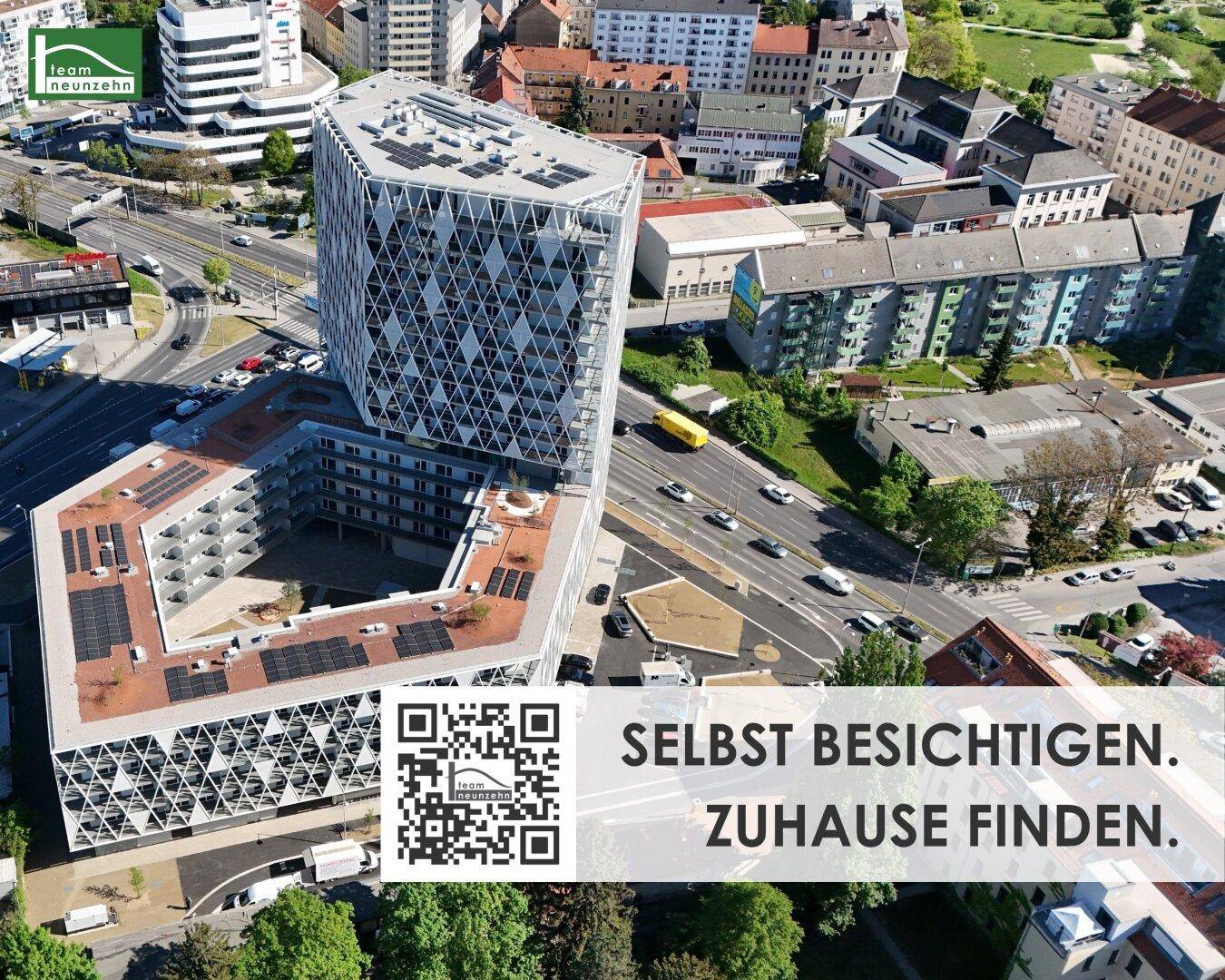 Luftaufnahme eines modernen Gebäudekomplexes mit markanter Architektur, Solarpaneelen auf den Dächern und städtischer Umgebung.