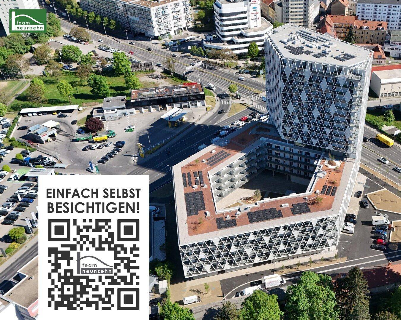 Luftaufnahme eines modernen Gebäudekomplexes mit geometrischer Fassade, Solarpaneelen und städtischer Umgebung.