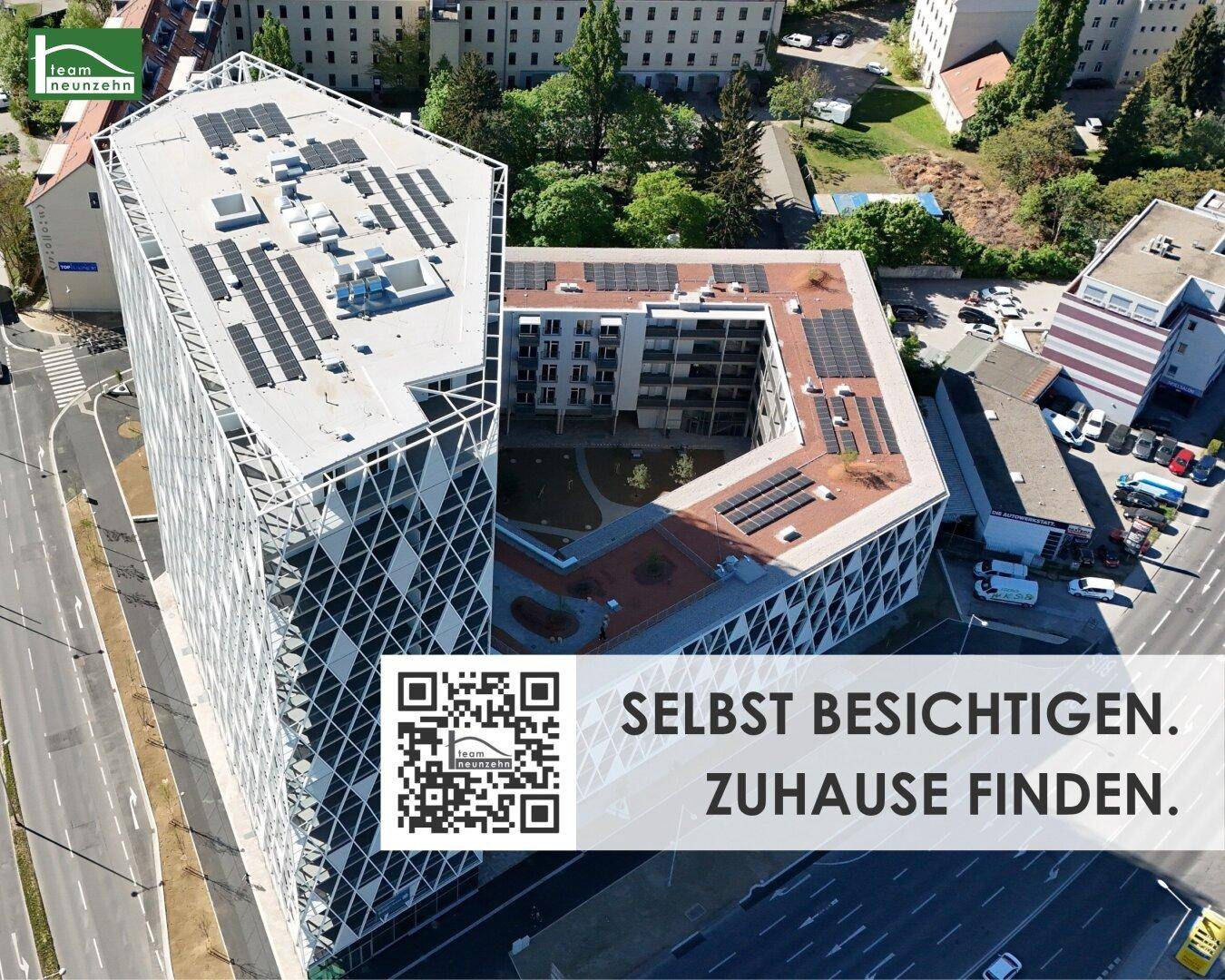Luftaufnahme eines modernen Gebäudekomplexes mit markanter Glasfassade, Flachdach und Photovoltaikanlage. Ein begrünter Innenhof ist ebenfalls sichtbar.