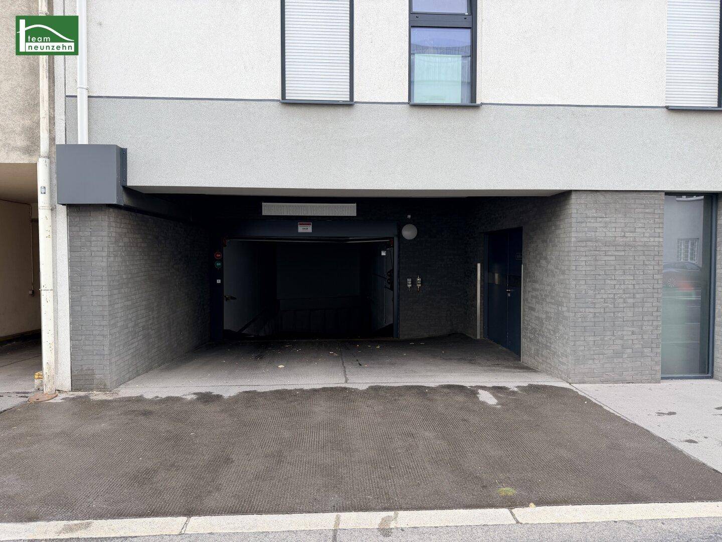 Einfahrt zur Tiefgarage des modernen Wohnkomplexes mit dunklen Ziegelwänden.