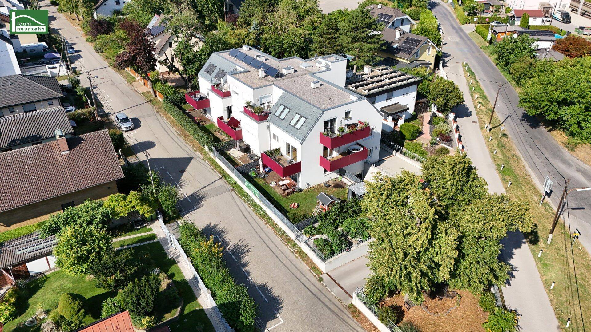 Weitläufige Luftaufnahme des Wohnkomplexes mit Garten, Balkonen und umliegender grüner Landschaft.