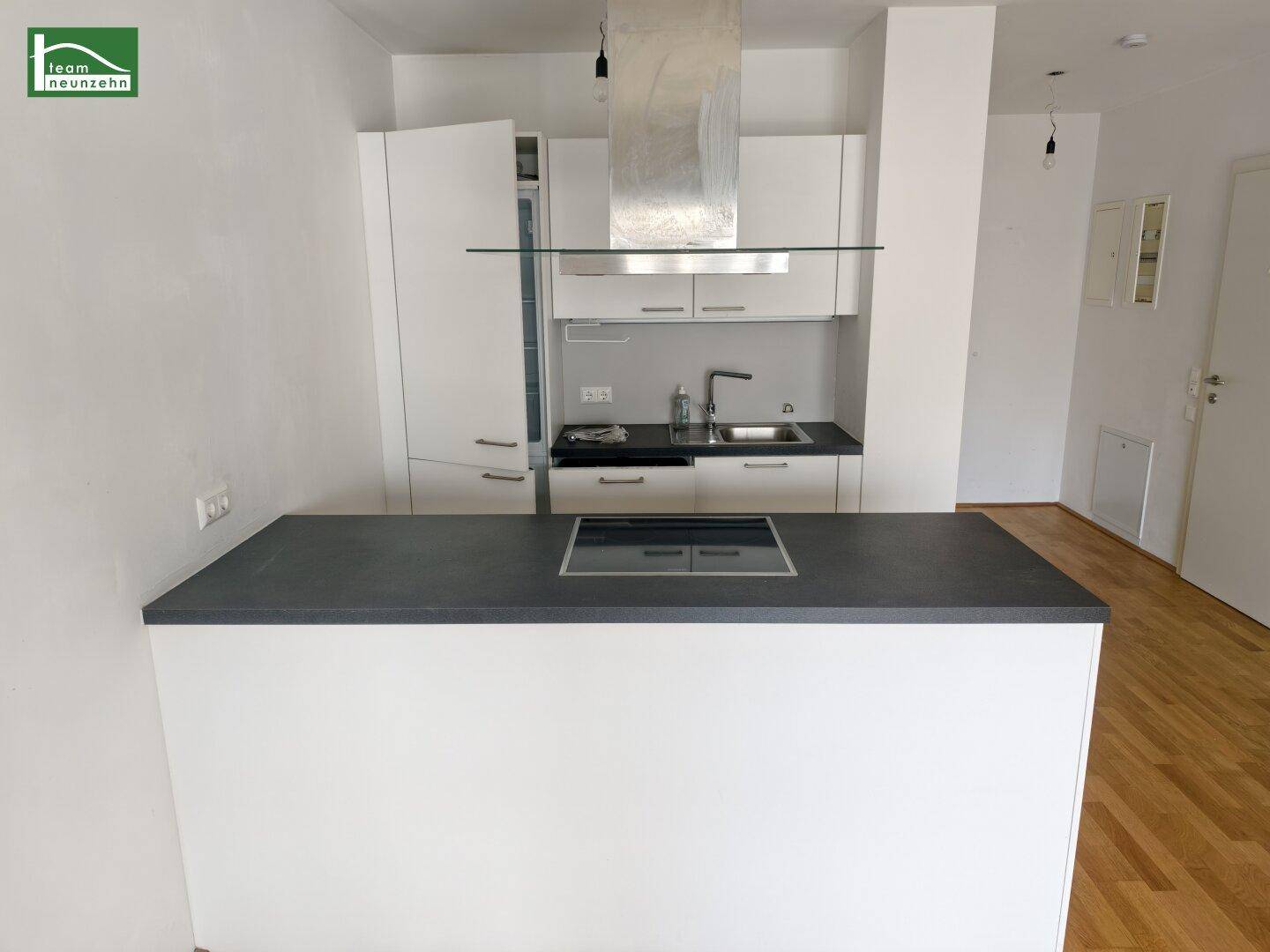 Moderne Einbauküche mit dunkler Arbeitsplatte, Induktionskochfeld und integrierten Geräten.