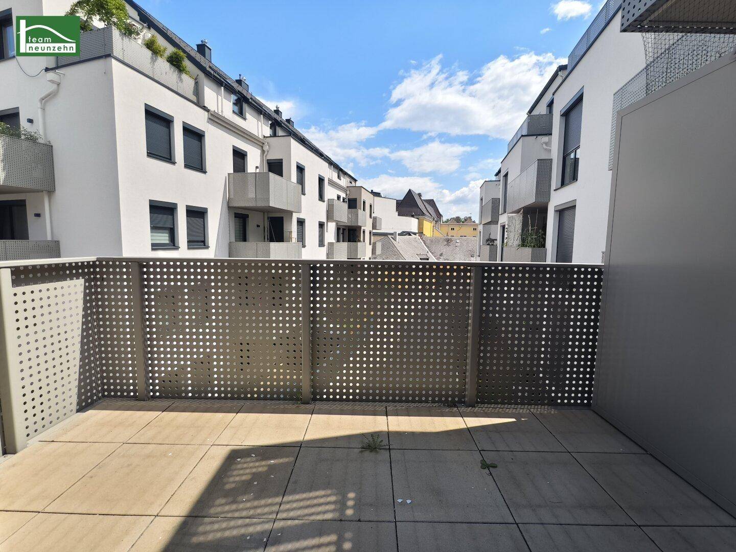 Geräumiger Balkon mit Fliesenboden und Blick auf die umliegenden modernen Gebäude.