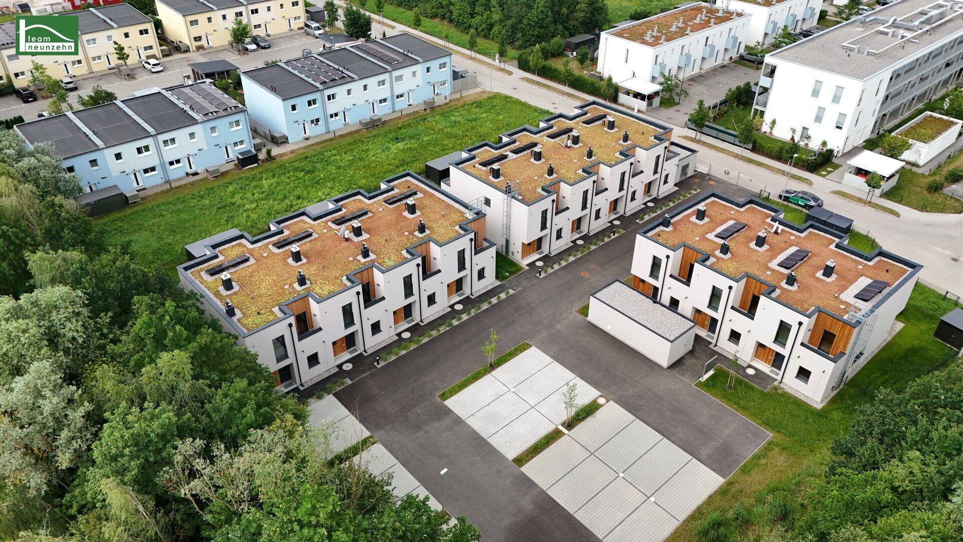 Überblick über die moderne Wohnanlage mit Reihenhäusern, Parkplätzen und umgebender Natur.