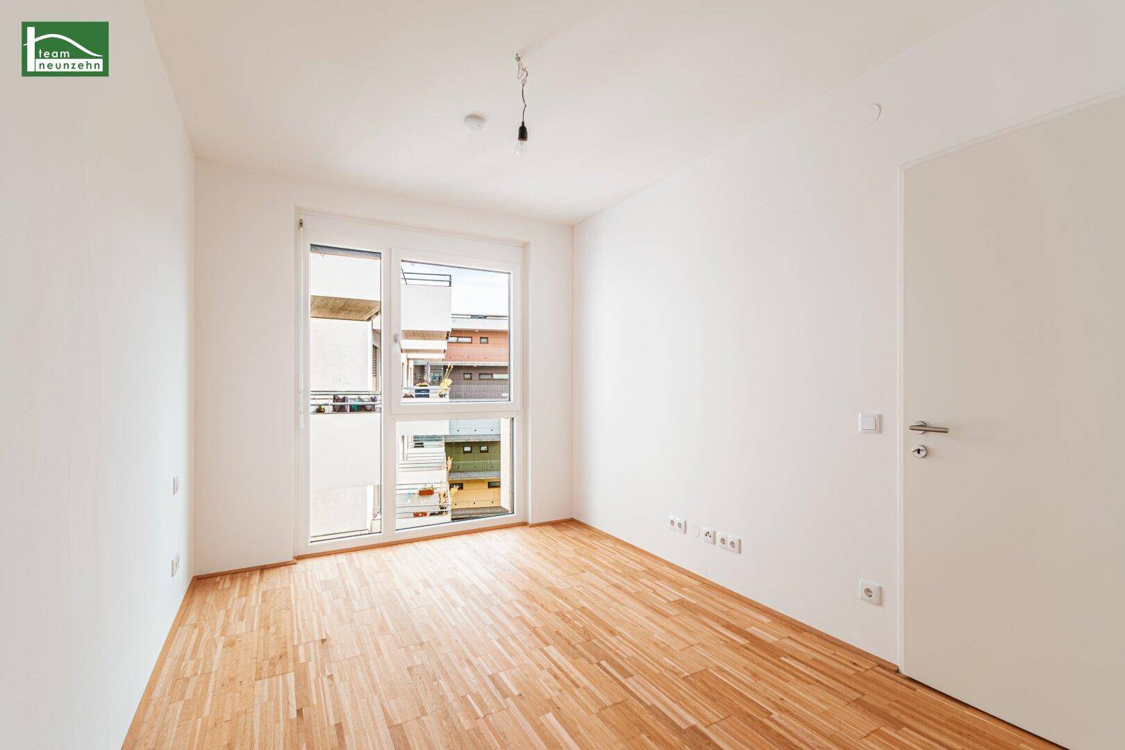 Helles Schlafzimmer mit Zugang zum Balkon und hellem Parkettboden.