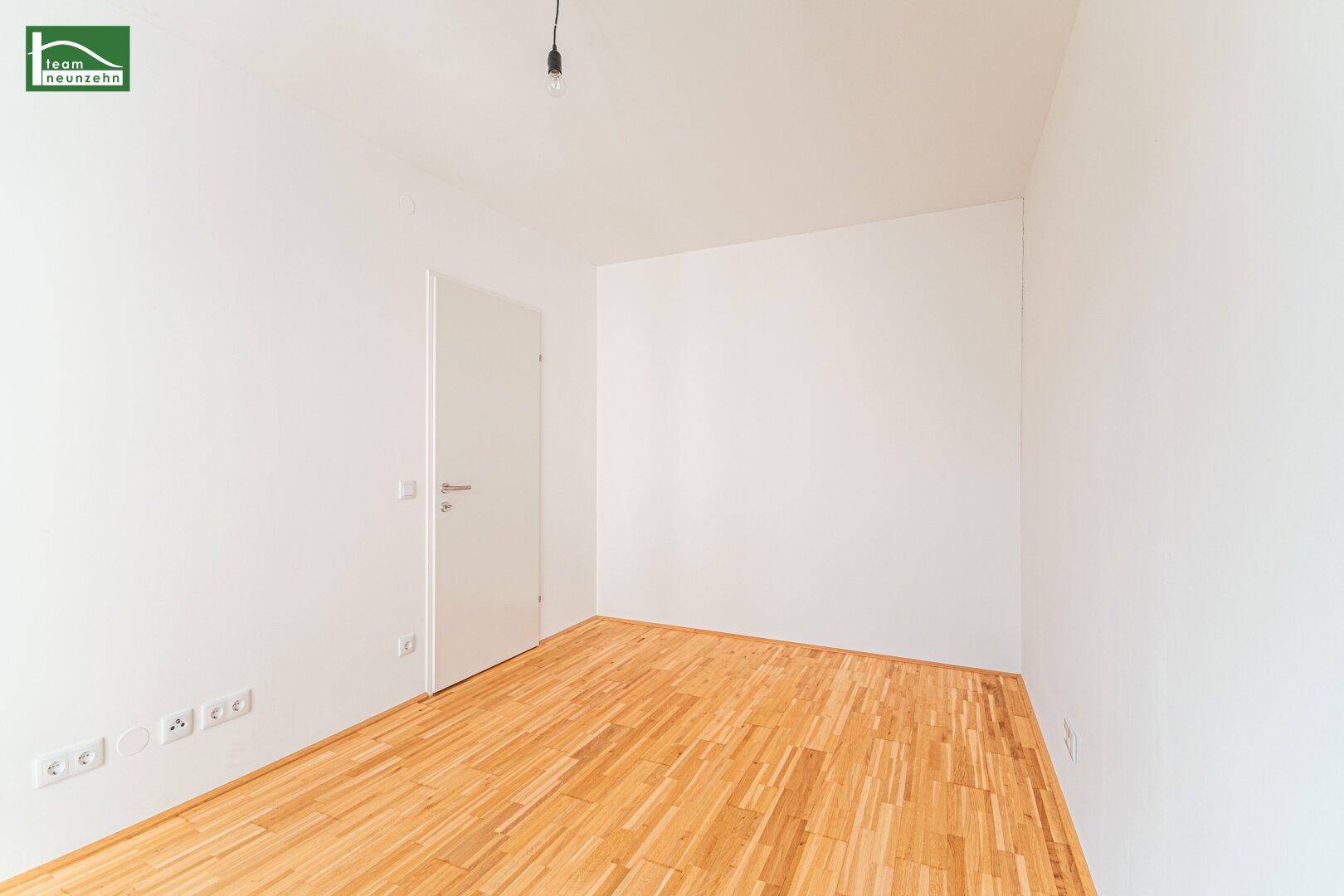 Leeres Schlafzimmer mit hellem Parkettboden und weiß gestrichenen Wänden.
