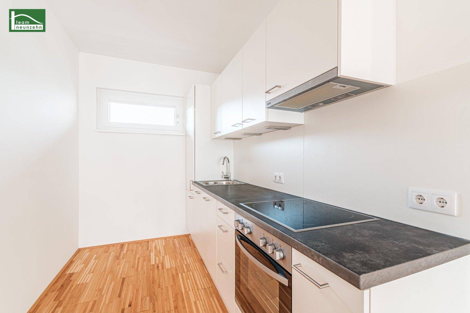 Moderne Küchenzeile mit Induktionskochfeld, Backofen und Dunstabzugshaube in weißem Design.