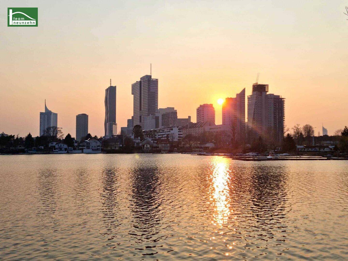Spektakulärer Sonnenuntergang über der Wiener Skyline mit modernen Hochhäusern und der Donau im Vordergrund.