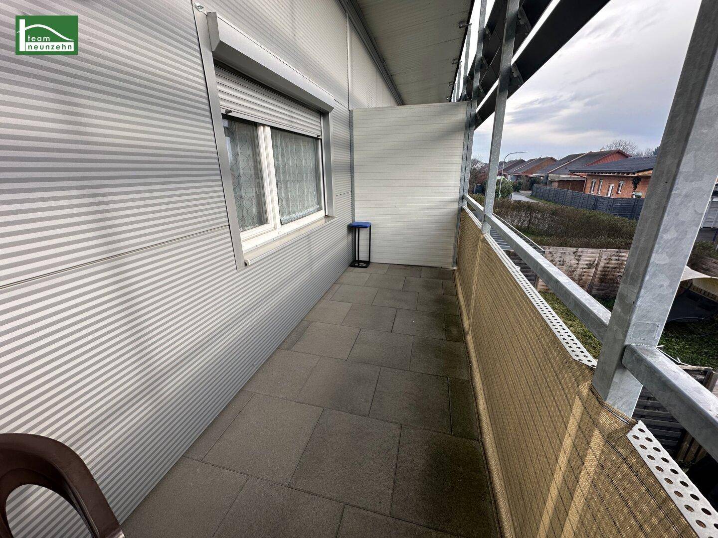Schmaler Balkon mit Fliesenboden und Metallgeländer, bietet Platz für einen kleinen Sitzbereich.