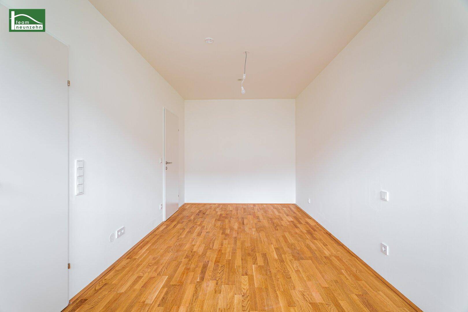 Heller, leerer Raum mit Holzboden und weißen Wänden, bereit zur individuellen Gestaltung.