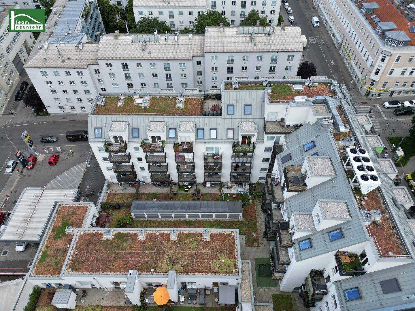 Blick von oben auf den begrünten Innenhof mit Balkonen und Dachterrassen.