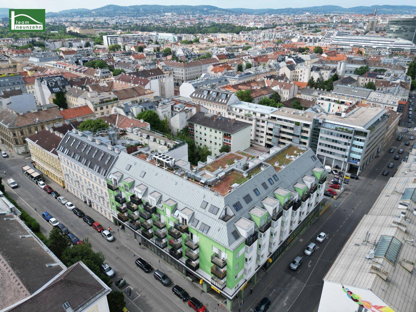 Luftaufnahme des modernen Gebäudekomplexes mit grünen Fassaden und Balkonen in der Stadt.