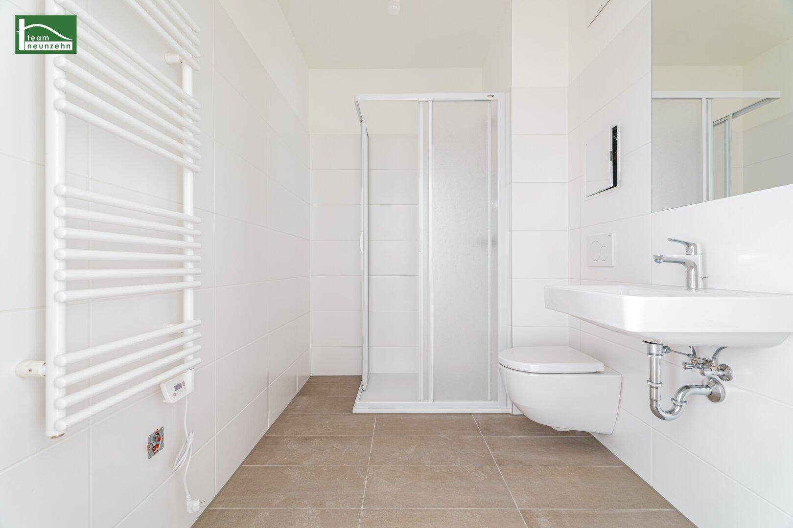 Modernes Badezimmer mit weißen Fliesen, Duschkabine, wandhängendem WC und Handtuchheizkörper.