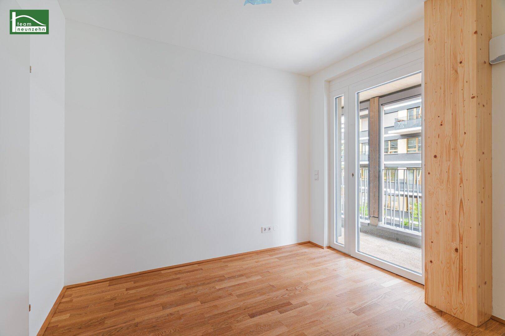 Helles Schlafzimmer mit Holzboden und Balkonzugang, perfekt für entspannte Morgenstunden.
