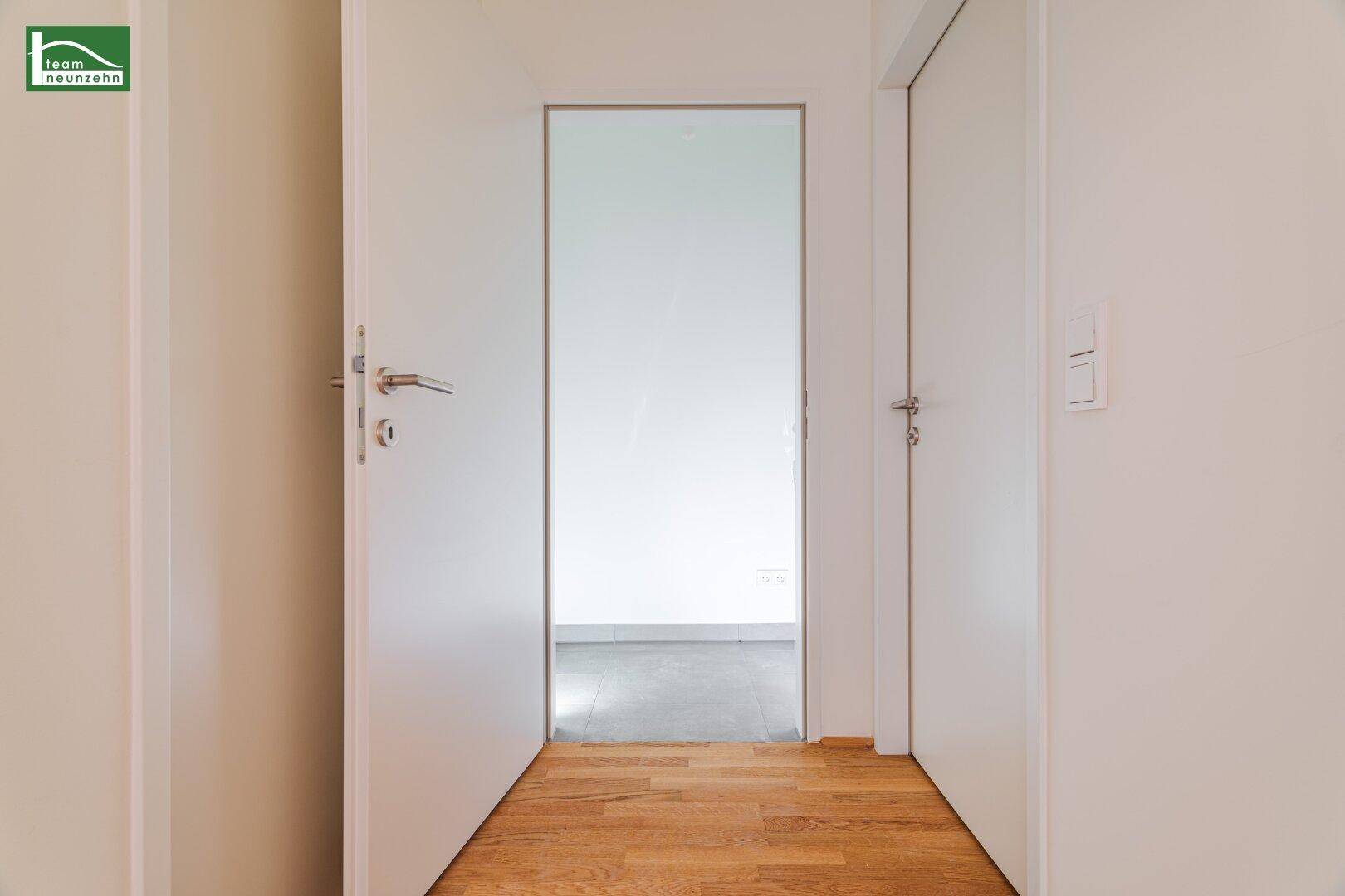 Heller Flur mit Holzboden und weißen Türen, der den Zugang zu weiteren Räumen ermöglicht.