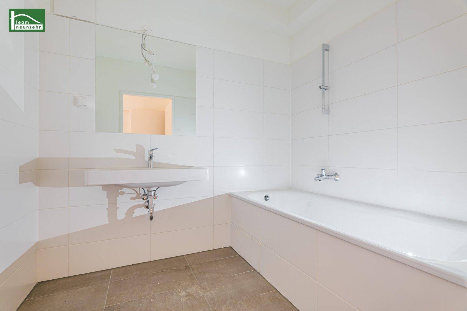 Modernes Badezimmer mit Badewanne, Waschbecken und weißen Fliesen an den Wänden.