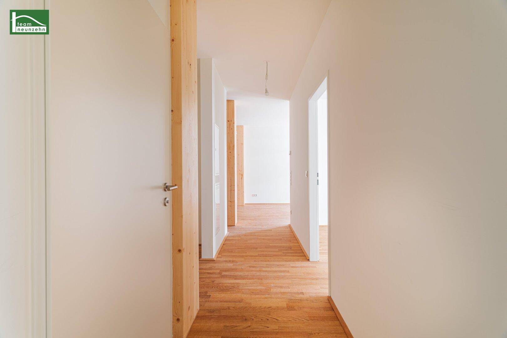 Langer Flur mit Holzboden und Holzsäule, der zu verschiedenen Räumen führt.