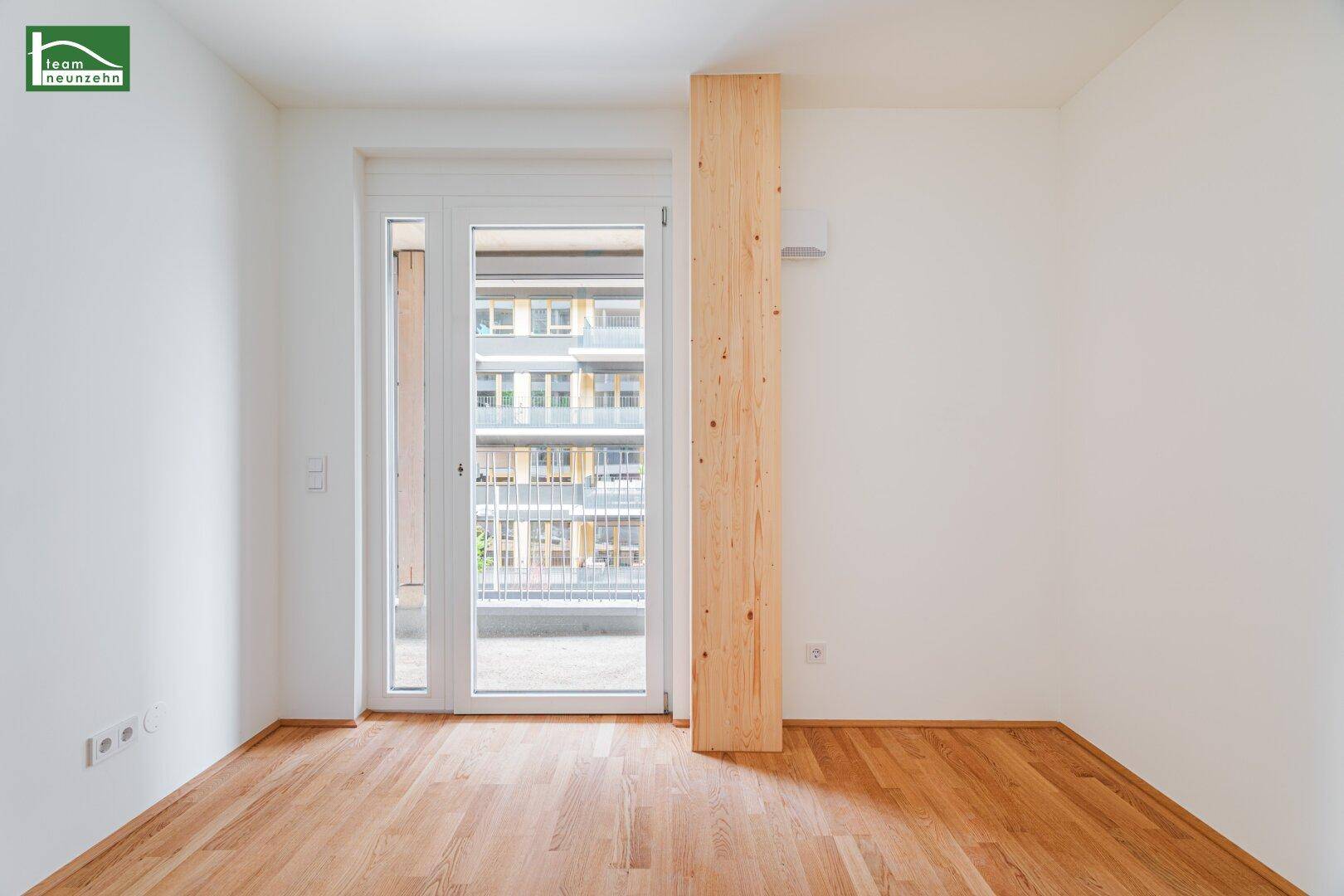 Lichtdurchfluteter Raum mit Balkontür und Holzfußboden, bietet Zugang zum Außenbereich.
