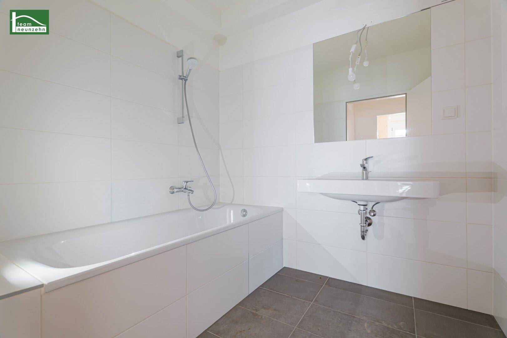 Modernes Badezimmer mit Badewanne, Waschbecken und weißen Fliesen.