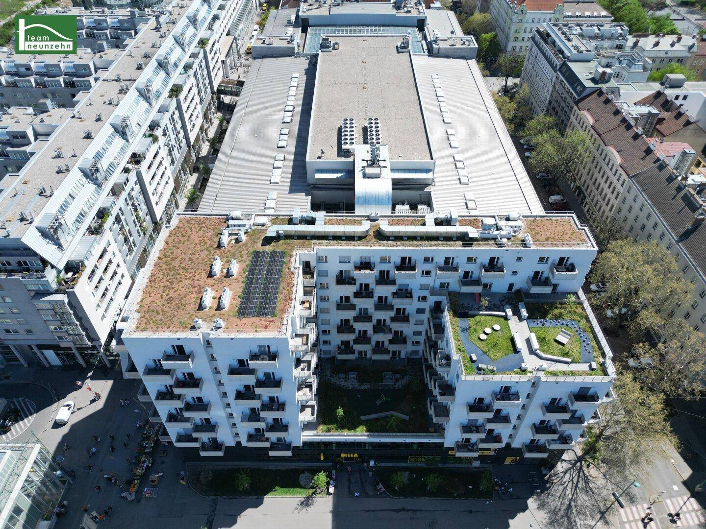 Luftaufnahme eines modernen Wohnkomplexes mit begrünten Dächern und Innenhof.