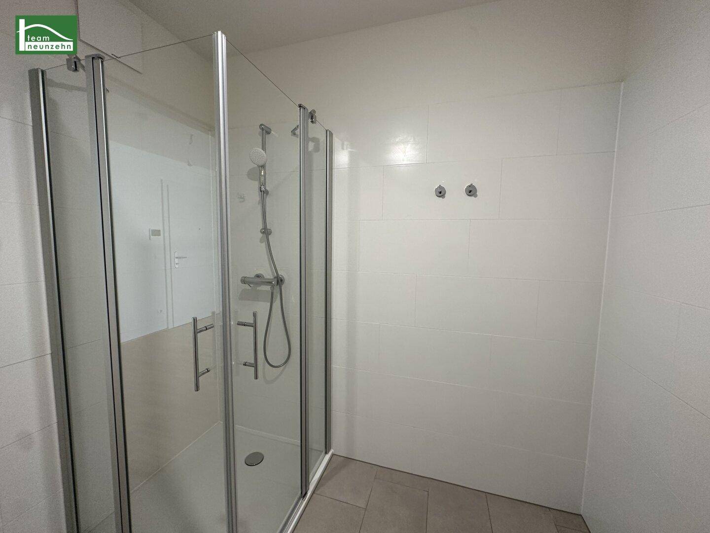 Modernes Badezimmer mit einer geräumigen Duschkabine und weißen Wandfliesen.