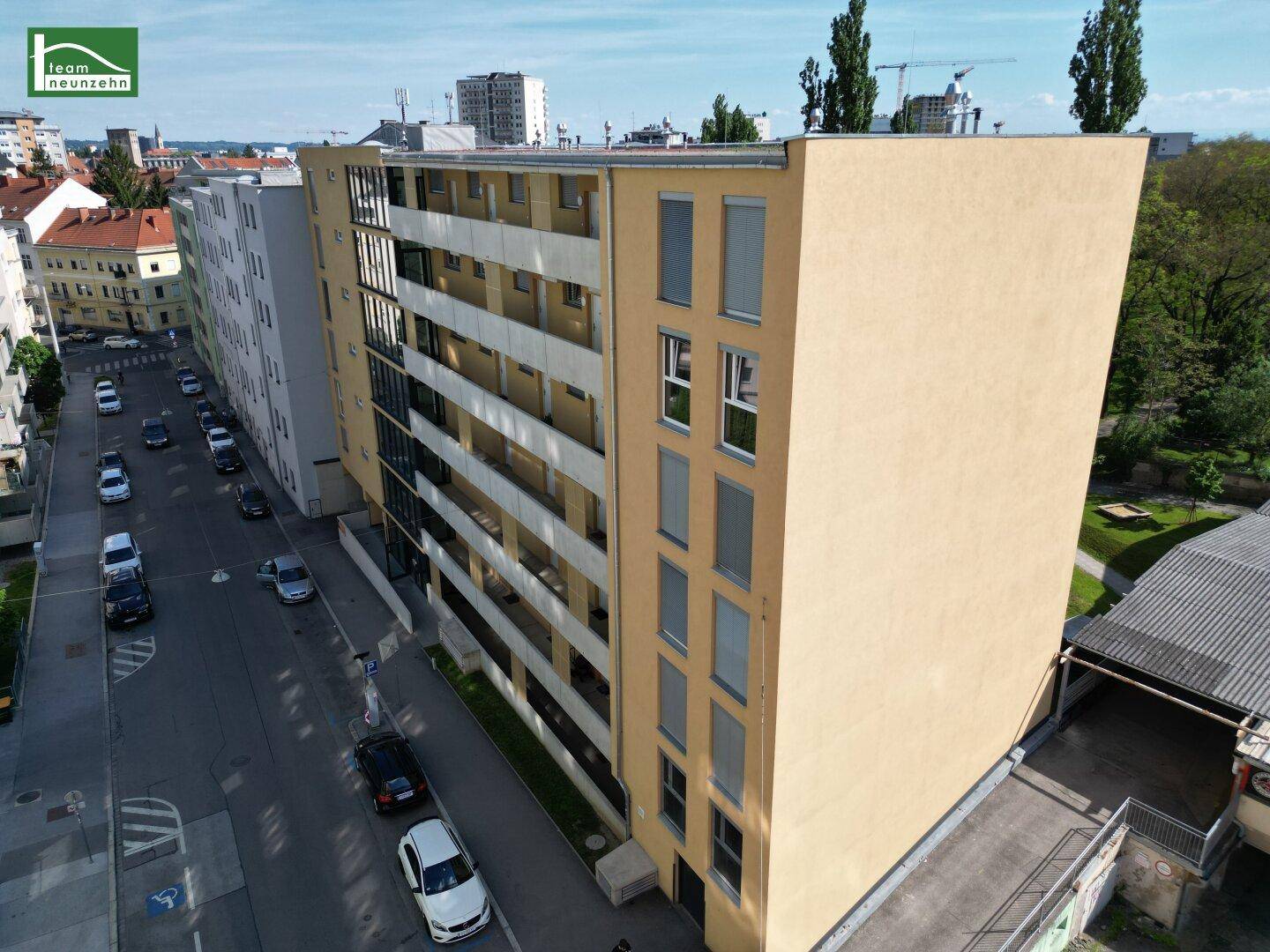 Seitenansicht der modernen Wohnhausfassade mit Balkonen und großen Fenstern zur Straße.