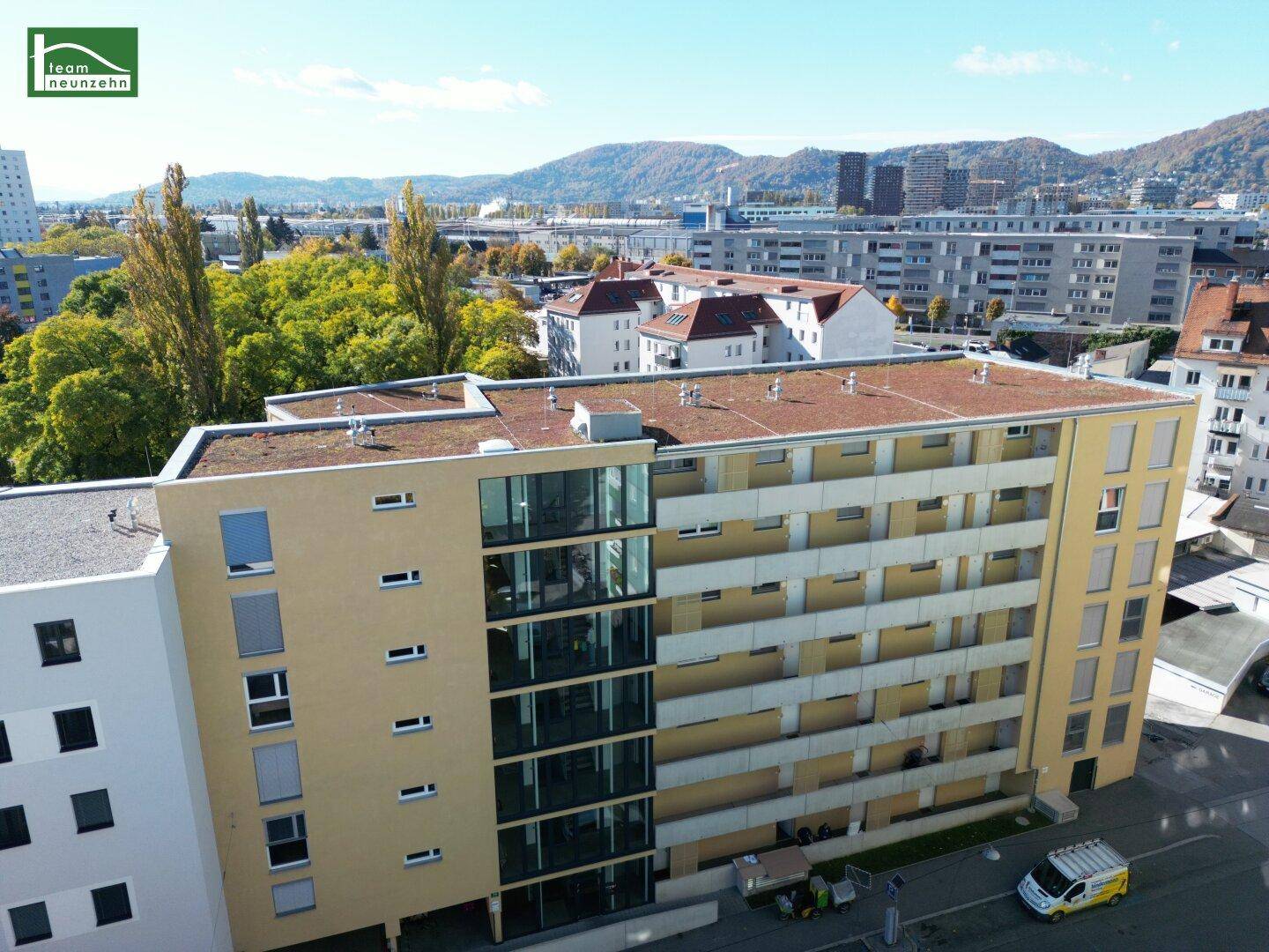 Luftaufnahme der modernen Wohnhausfassade mit Balkonen und großen Glasflächen.