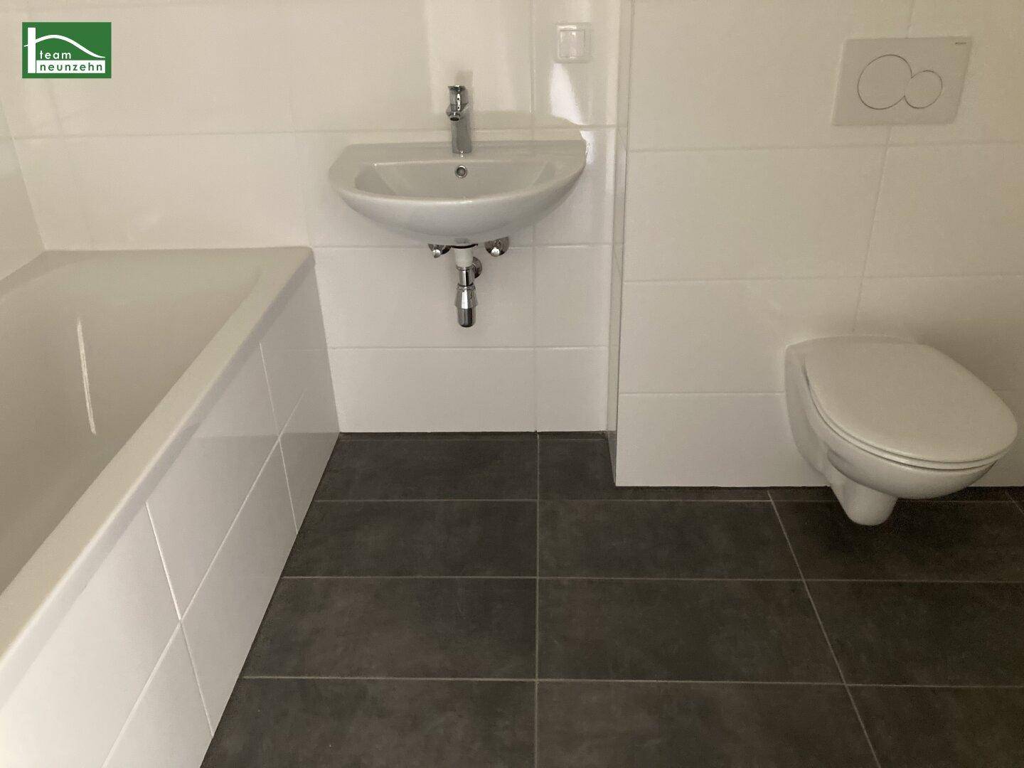Modernes Badezimmer mit Badewanne, Waschbecken und wandhängendem WC in hellen Fliesen.
