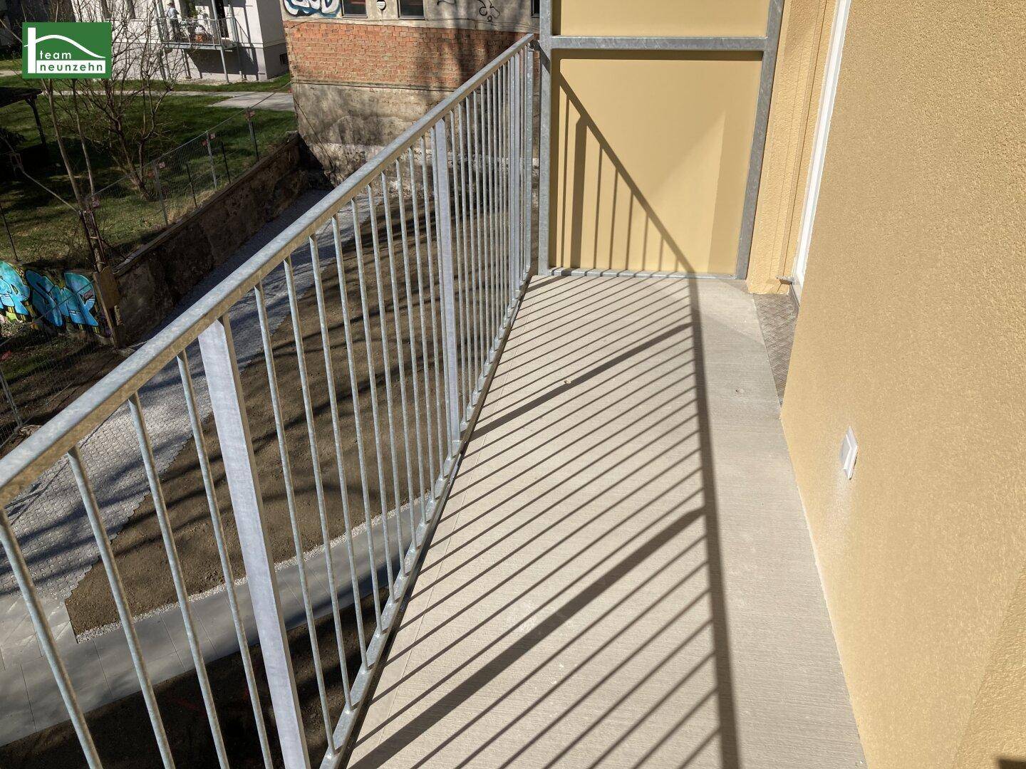 Sonniger Balkon mit schlichtem Metallgeländer und Blick auf die umliegenden Gebäude.