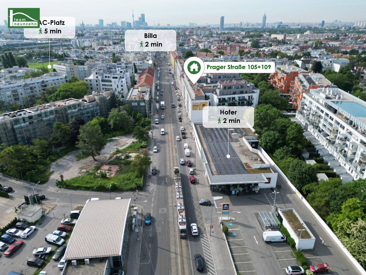 Luftbild einer Hauptstraße mit Geschäften, Wohngebäuden und einer Straßenbahnlinie.