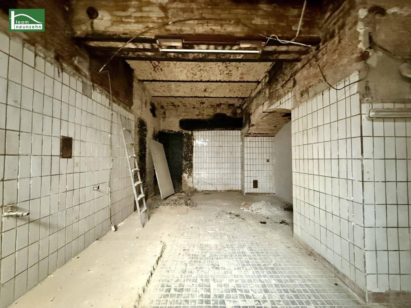 Dieser Kellerraum ist renovierungsbedürftig mit gefliesten Wänden und einer freiliegenden Ziegeldecke.