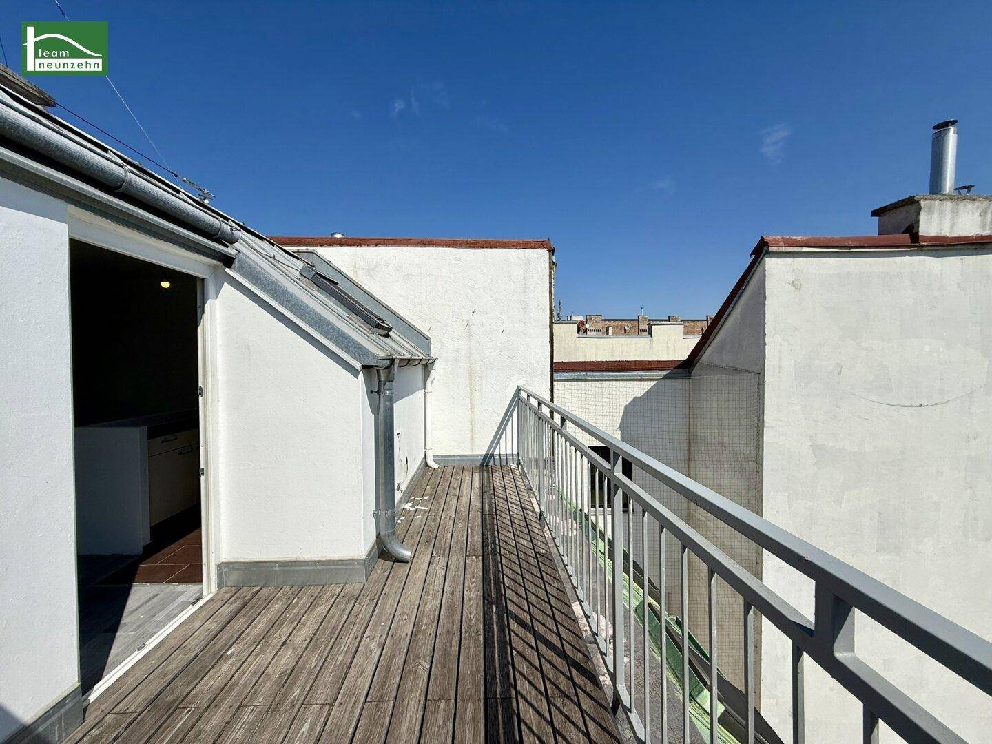Geräumige Dachterrasse mit Holzbelag und Metallgeländer, ideal für entspannte Stunden im Freien.