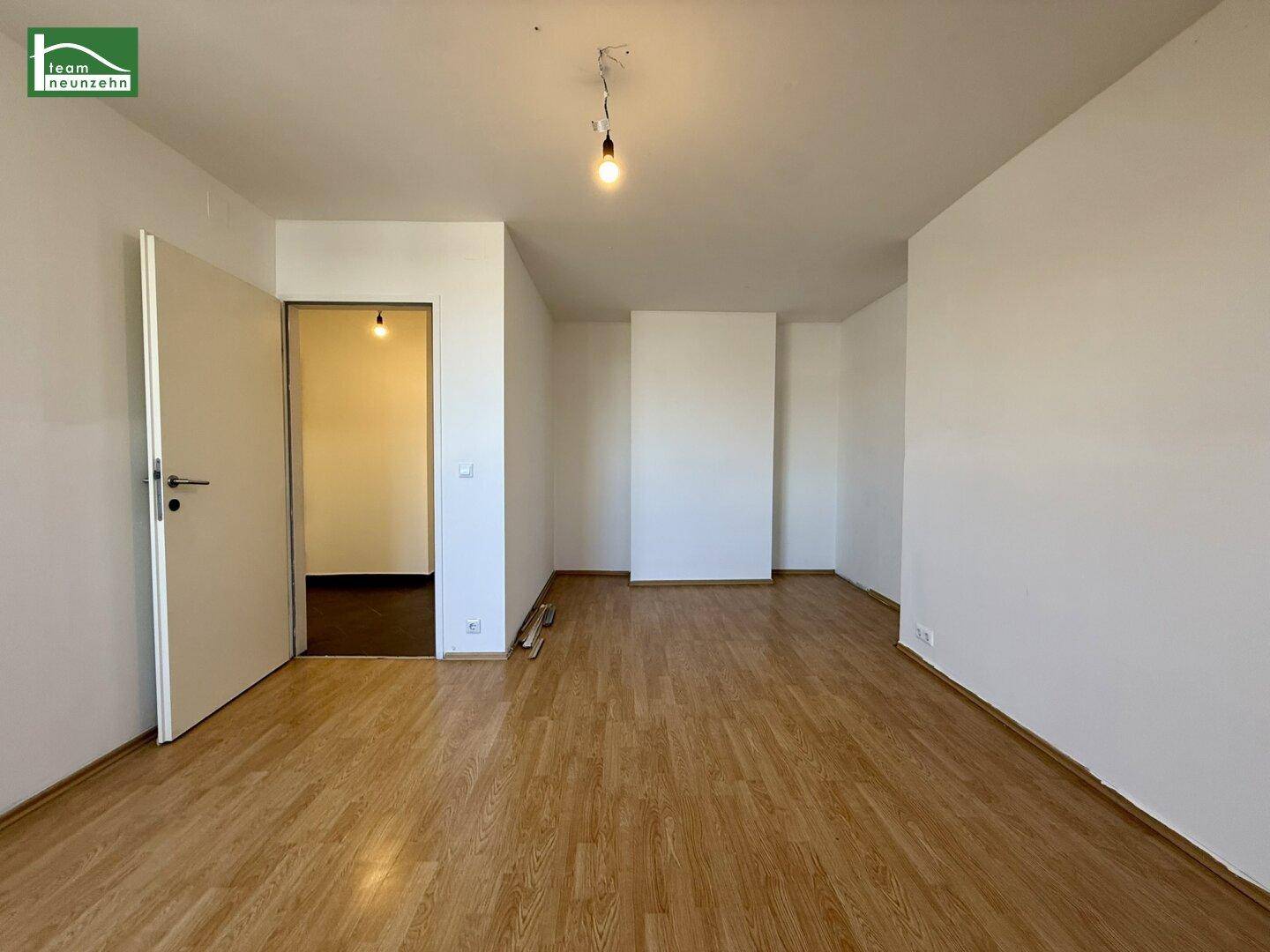 Heller, leerer Raum mit Holzfußboden und weiß gestrichenen Wänden, bereit zur individuellen Gestaltung.