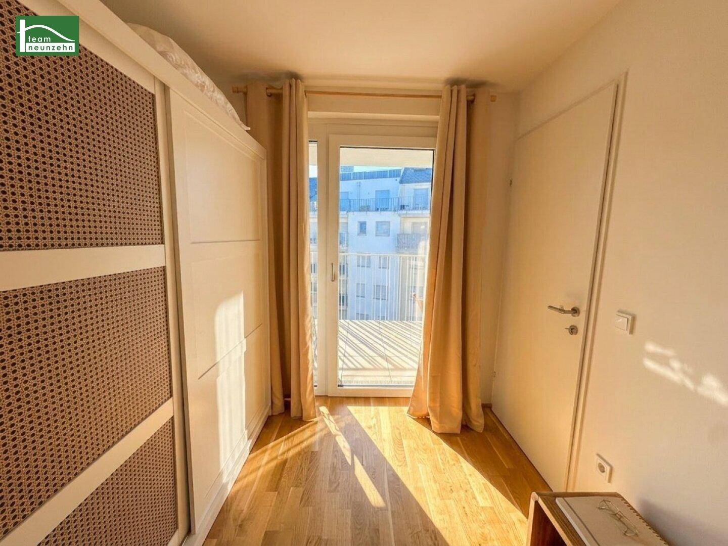 Helles Schlafzimmer mit Holzboden, großem Kleiderschrank und direktem Zugang zum Balkon.