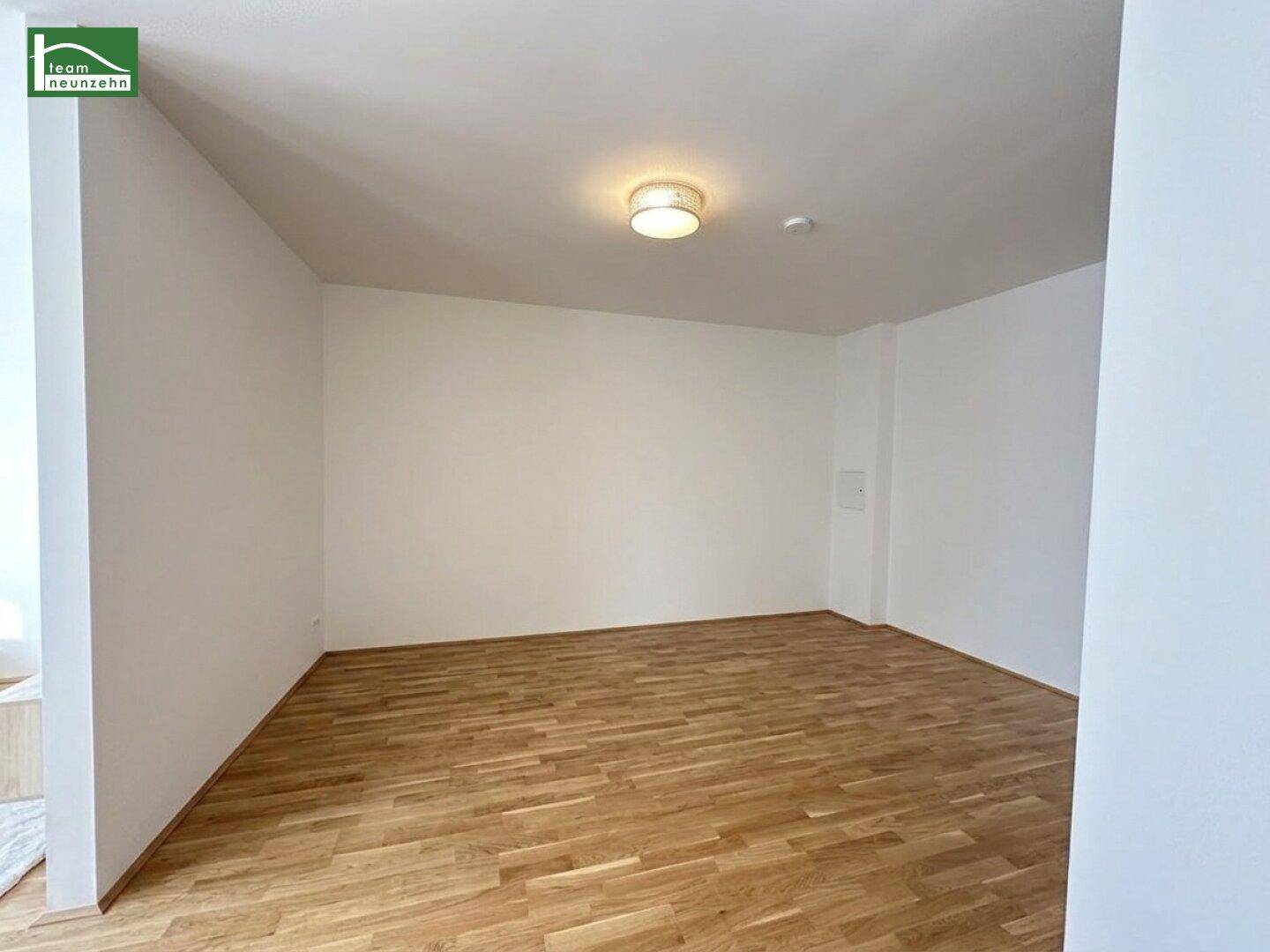 Leerer, heller Raum mit Holzboden und weiß gestrichenen Wänden, ideal für individuelle Gestaltung.