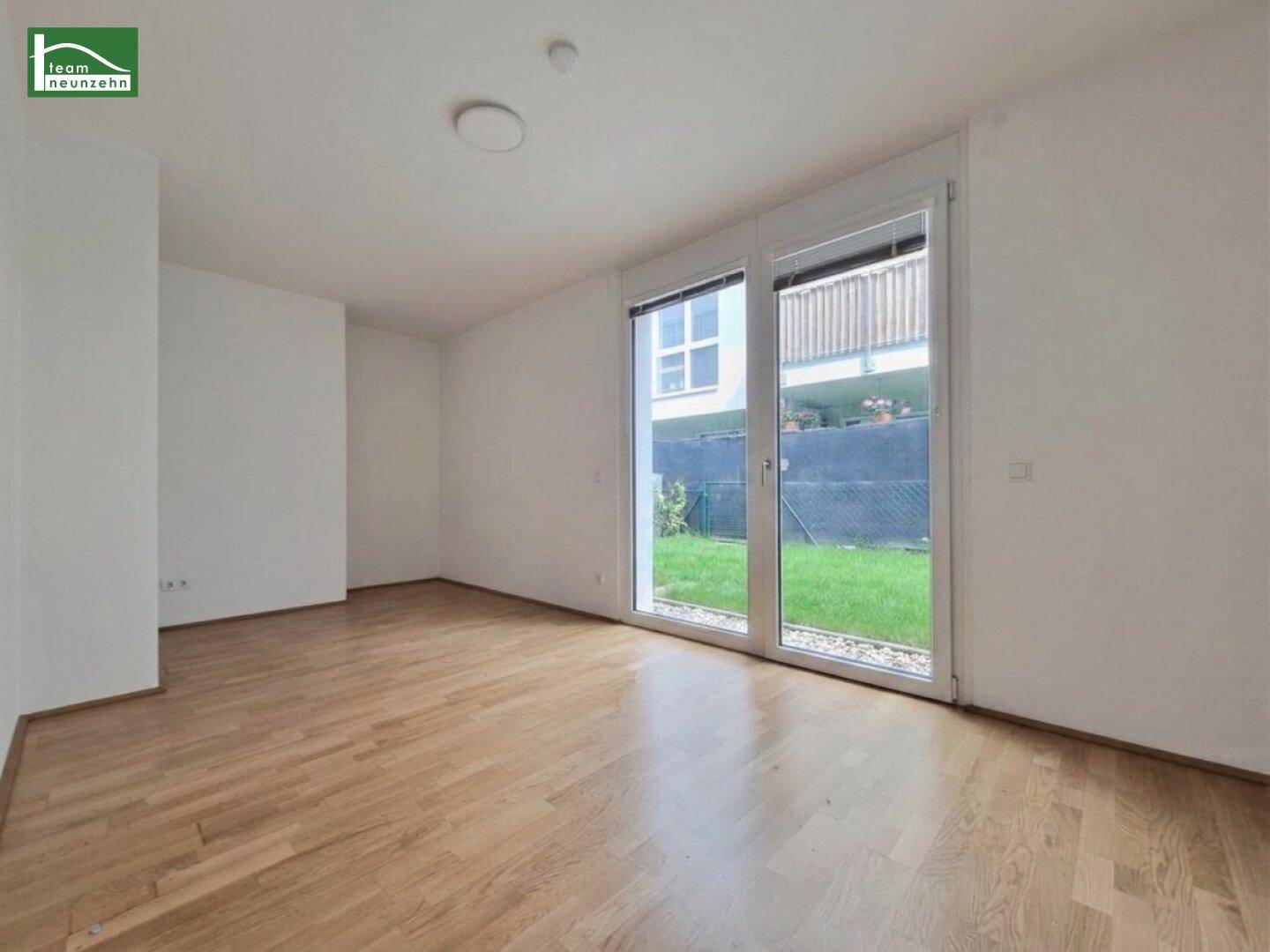Unmöbliertes Schlafzimmer mit Parkettboden und großen Fenstern, die viel Tageslicht hereinlassen.