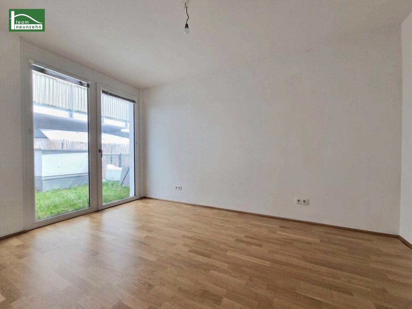 Leerer Raum mit Holzboden und großen Fenstern, die Zugang zum Außenbereich bieten.